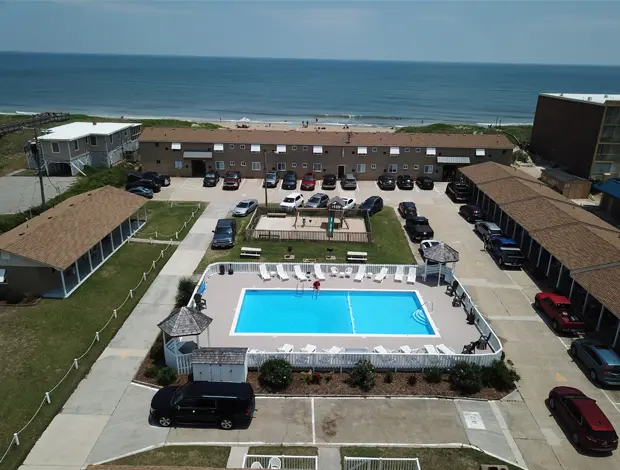 Aerial view of the Outer Banks Motor Lodge, its outdoor pool and parking area, with the Atlantic Ocean beyond