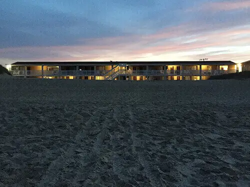 The motel building lit up at dusk, its windows glowing against the darkening sky