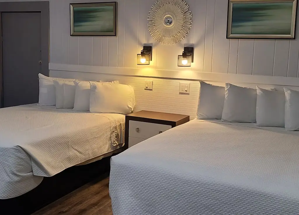 Two queen beds beside an accessible bathroom with a roll-in shower