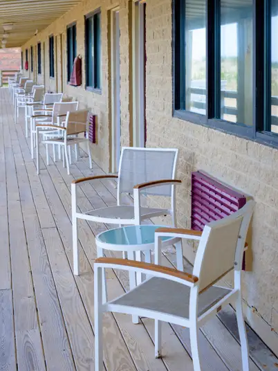 A second-floor balcony with two rocking chairs and a small table, looking out over the property
